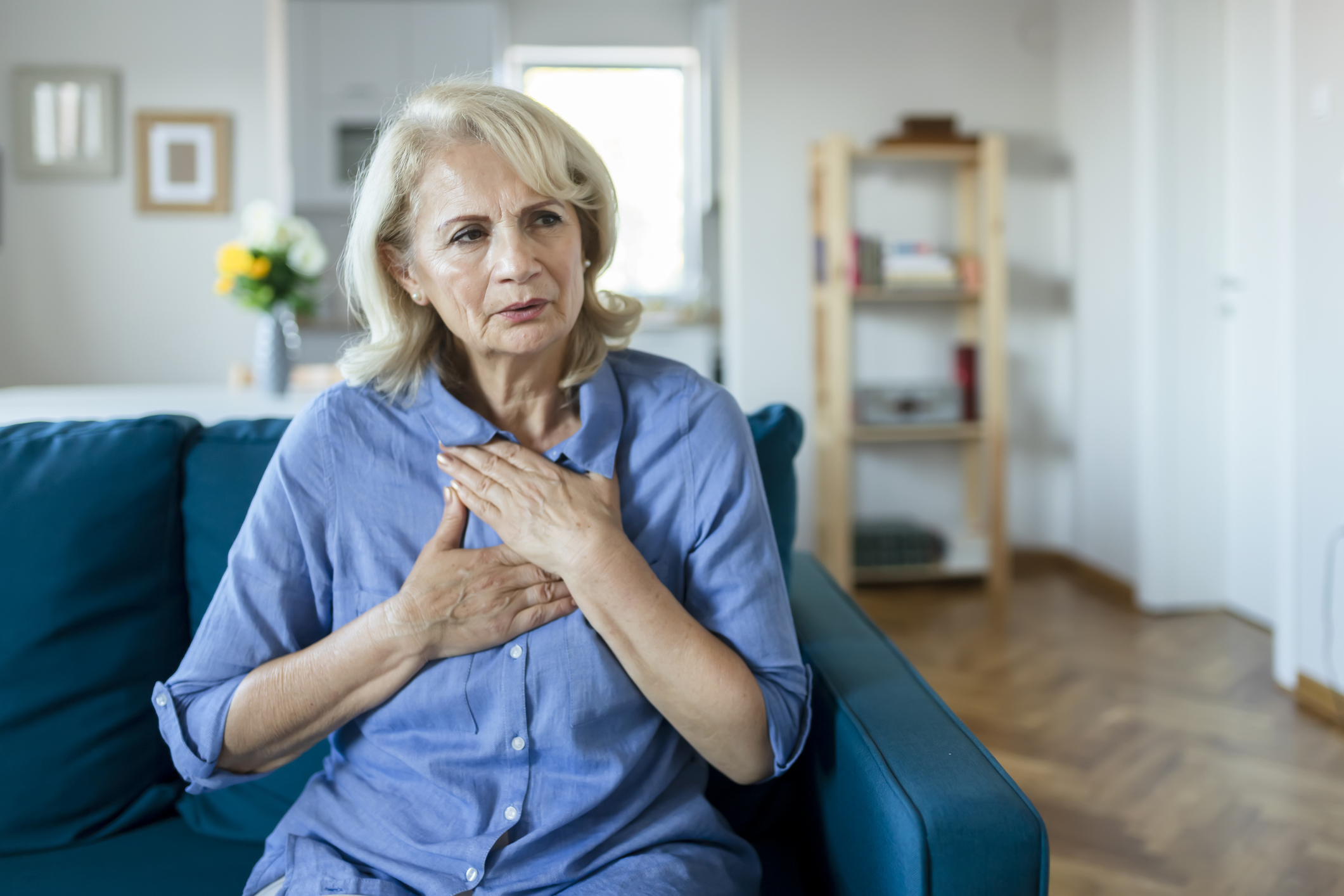 Senior woman with hands placed on chest from pain