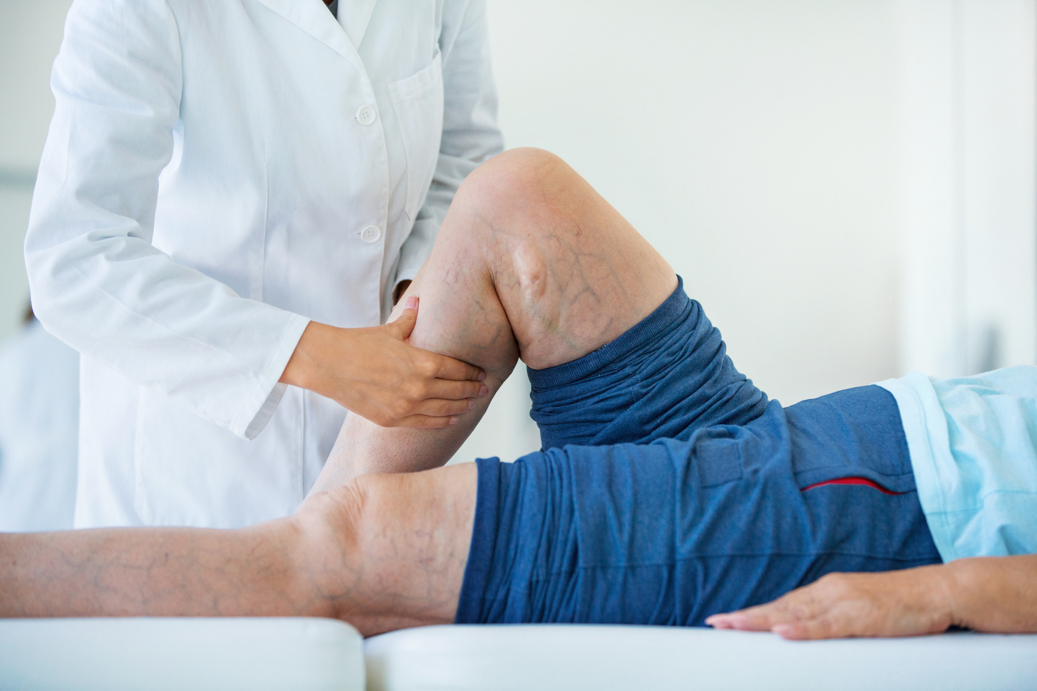 Senior woman receiving vein massage treatment on legs